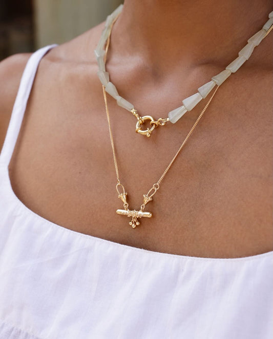Indian inspired hand made solid silver 22k Gold plated bar necklace with a pendant on a person wearing a white top.